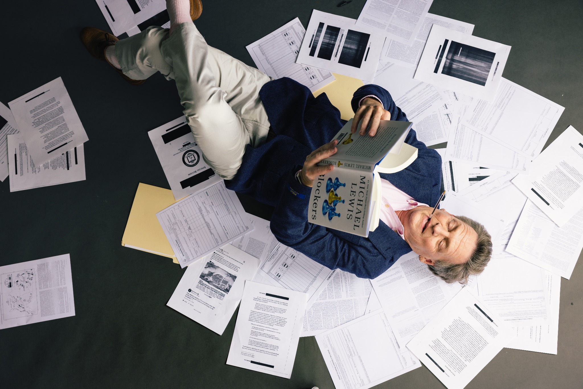 Michael Lewis reclining on manuscript pages with Blockers — photograph by Danny Bristoll