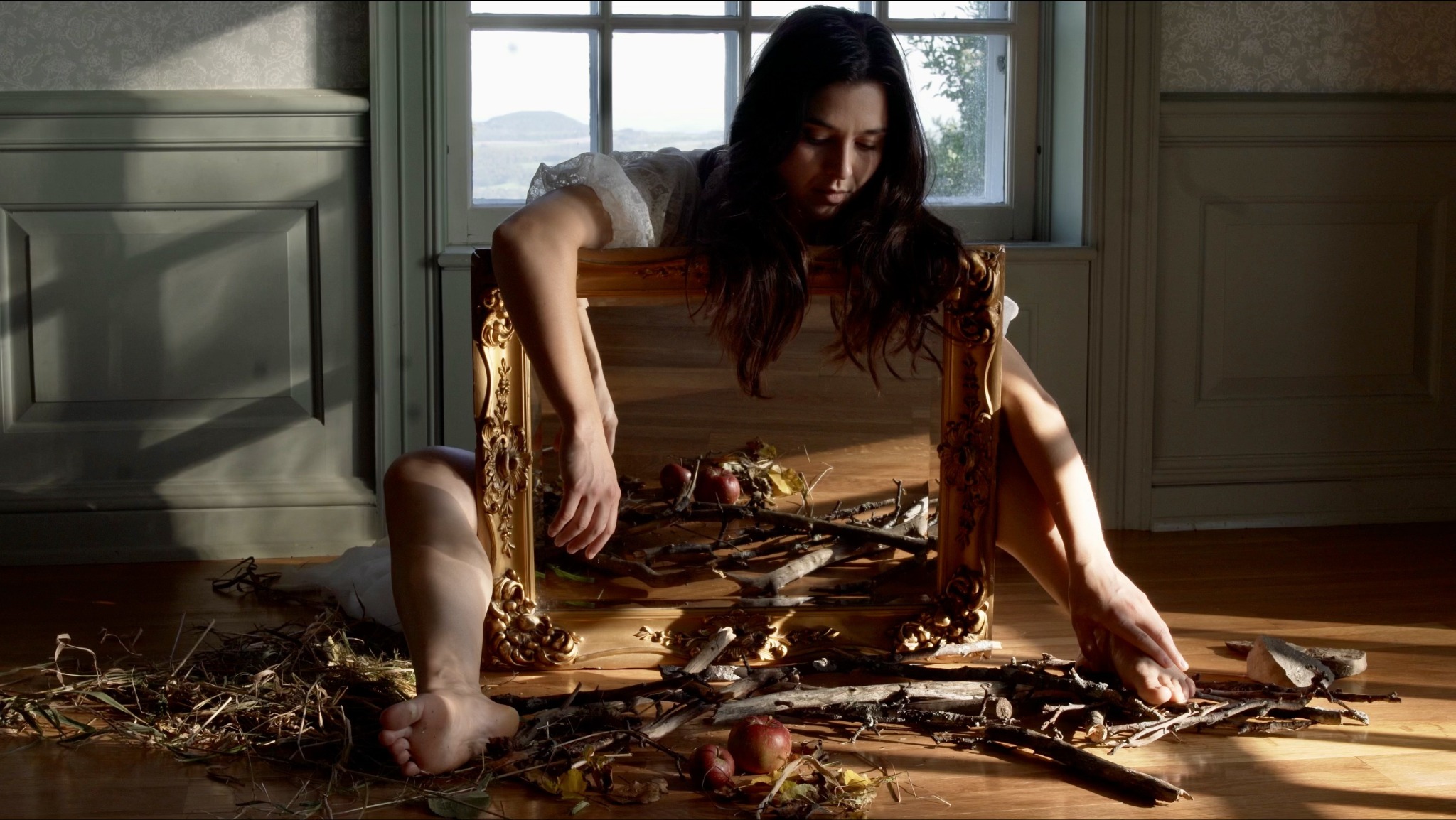 Emily Jeanne Brown among branches in a sunlit room — Nina music video still